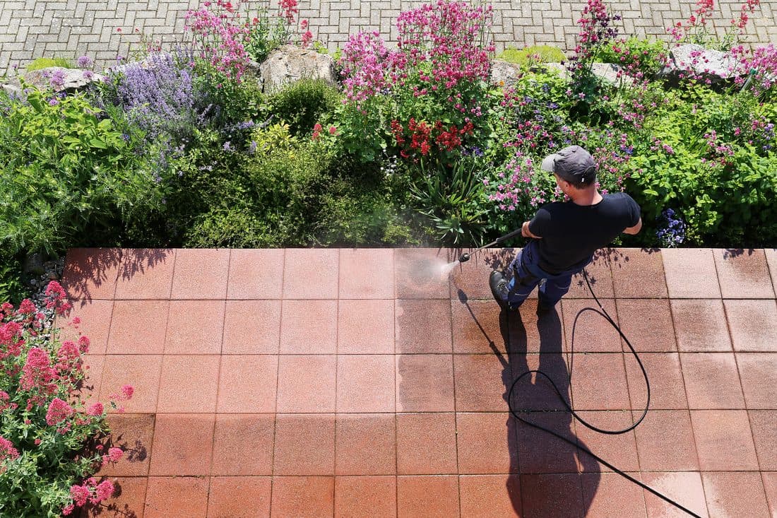 Commercial facilities technician power washing a warehouse exterior